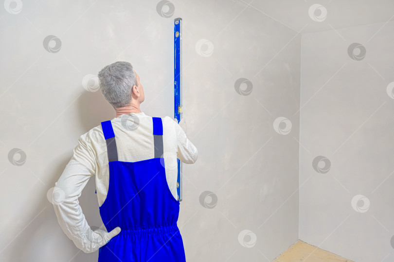 Скачать Строитель проверяет вертикальность оштукатуренной поверхности фотосток Ozero