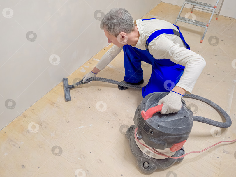 Скачать Мужчина моет пол пылесосом. В комнате сделан ремонт фотосток Ozero