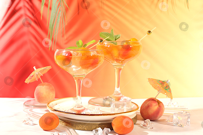 Скачать Современный натюрморт с алкогольным коктейлем или пуншем, ягодами персика, абрикоса и мяты на элегантном фоне, минималистичная концепция для бара и праздничной вечеринки, кафе, рекламного баннера фотосток Ozero