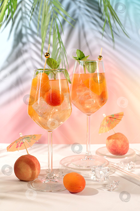 Скачать Современный натюрморт с фруктами. Коктейль "Королевский лимонад" с персиком, абрикосом, мохито с текилой, джином, ромом, льдом и свежей мятой, концепция бара и вечеринки, рекламная открытка ресторана и кафе. фотосток Ozero