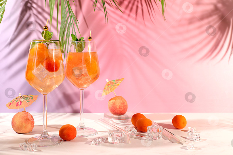 Скачать Современный натюрморт с фруктами. Коктейль "Королевский лимонад" с персиком, абрикосом, мохито с текилой, джином, ромом, льдом и свежей мятой, концепция бара и вечеринки, рекламная открытка ресторана и кафе. фотосток Ozero