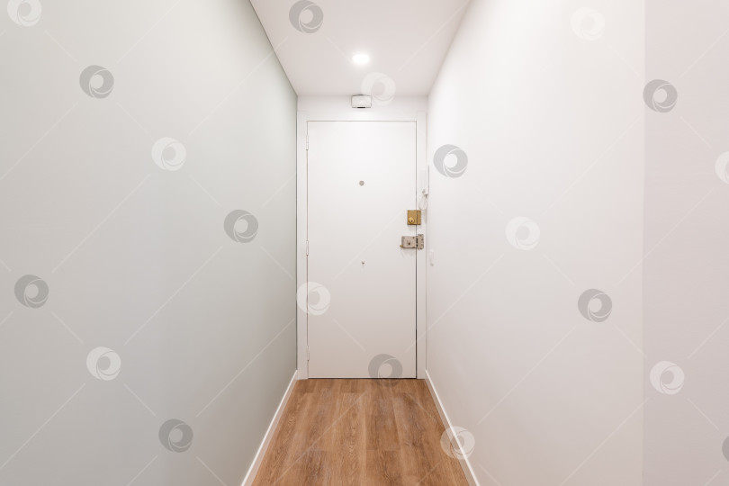 Скачать Вид на входную дверь в белом узком пустом коридоре в отеле или небольшой квартире для одного человека. Концепция компактных номеров для молодой пары или одноместного номера в отеле фотосток Ozero