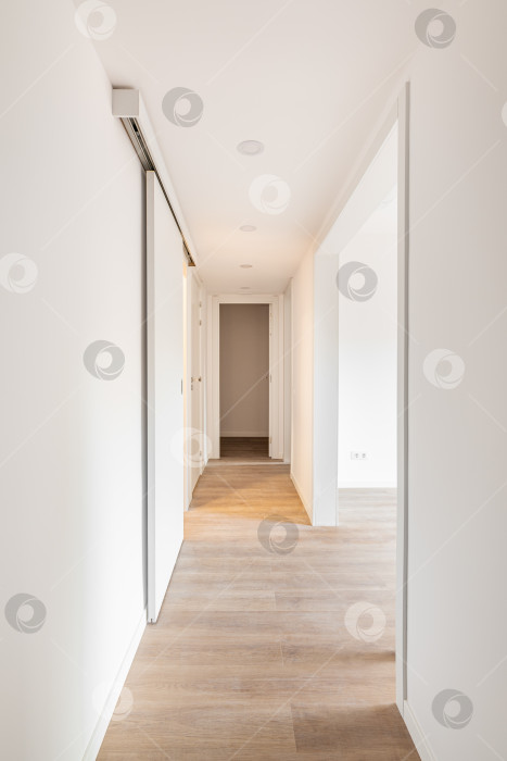 Скачать Белый коридор с входами в светлую комнату и раздвижными дверями в пустой квартире до переезда или после ремонта. Концепция реновации и реставрации старых помещений. Копировальное пространство фотосток Ozero
