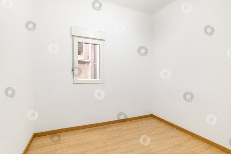 Скачать Небольшая компактная комната с маленьким окном и белыми стенами, ожидающая мебели и хозяев. Концепция покупки бюджетного жилья в ипотеку. Копировальное пространство фотосток Ozero