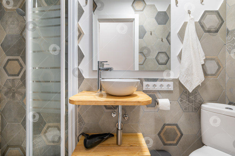 Скачать Серая многоугольная декоративная плитка в ванной комнате с застекленной душевой кабиной и умывальником. Концепция стильной дизайнерской ванной комнаты в квартире или загородном доме фотосток Ozero