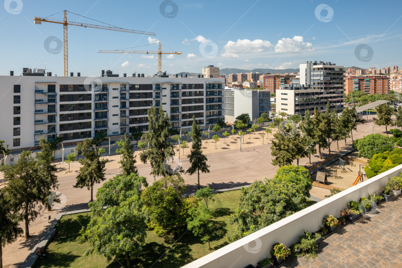Скачать В Горге, Барселона, Испания, строятся новые дома с помощью строительных кранов на фоне голубого неба в солнечный теплый летний день. Концепция новых роскошных комфортных районов в Европе фотосток Ozero
