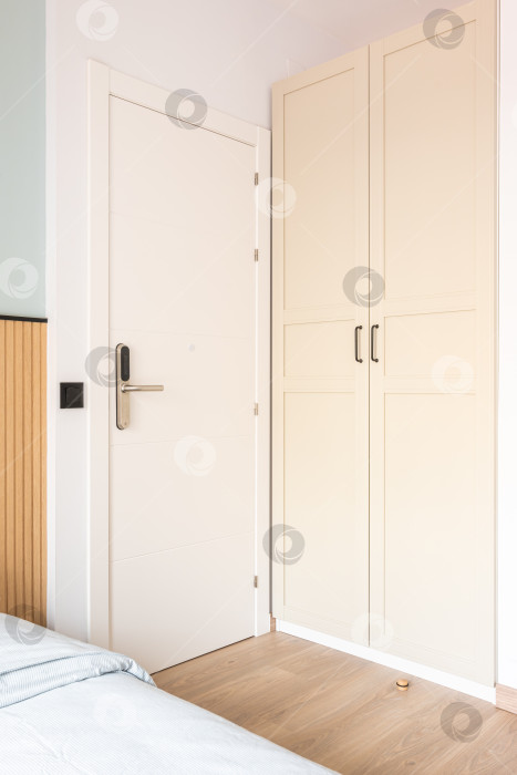 Скачать Вид на белые входные двери с электронным цифровым замком рядом со шкафом и кроватью в гостиничном номере. Концепция современной системы безопасности и предохранения фотосток Ozero