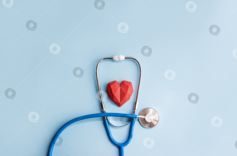 Скачать Медицинский стеноскоп и красное многоугольное сердце на синем фоне. Минимальная концепция кардиологии, пространство для копирования фотосток Ozero