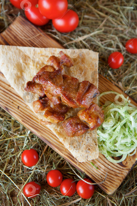Скачать Приготовленные на гриле мясные шашлыки выложите на деревянную доску. Украсьте овощами и тонким слоем хлеба. фотосток Ozero