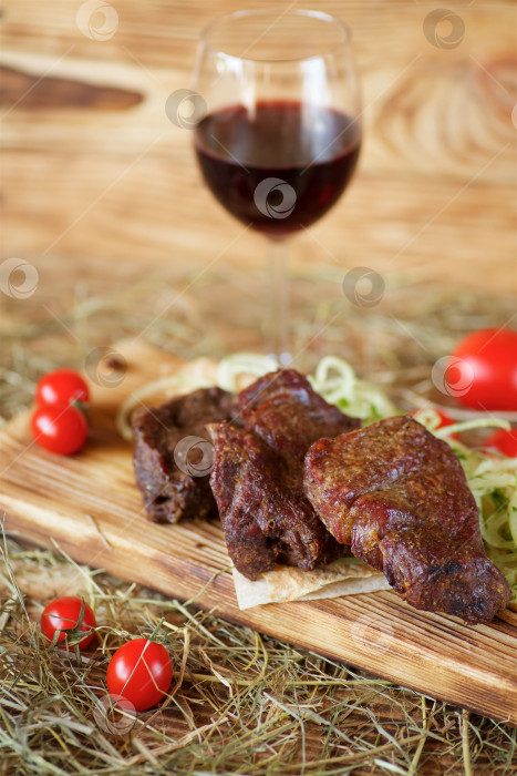 Скачать Приготовленные на гриле мясные шашлыки укладывают на деревянную доску. Украшают овощами и тонким хлебом. Блюда готовятся по рецептам шеф-повара. фотосток Ozero