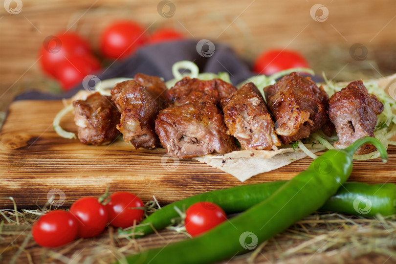 Скачать Приготовленные на гриле мясные шашлыки выложите на деревянную доску. Украсьте овощами и тонким хлебом. Приготовьте по рецептам шеф-повара. фотосток Ozero