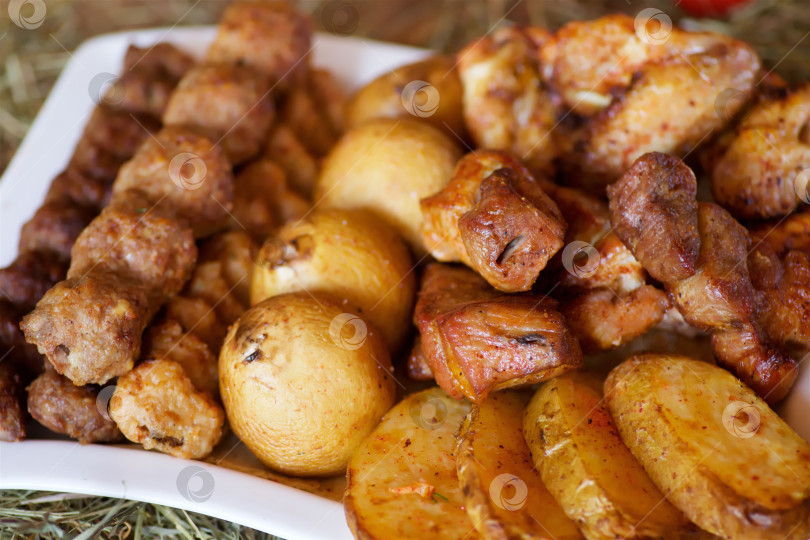 Скачать Мясные закуски, овощи и грибы, запеченные на гриле, лежат на большой тарелке. фотосток Ozero