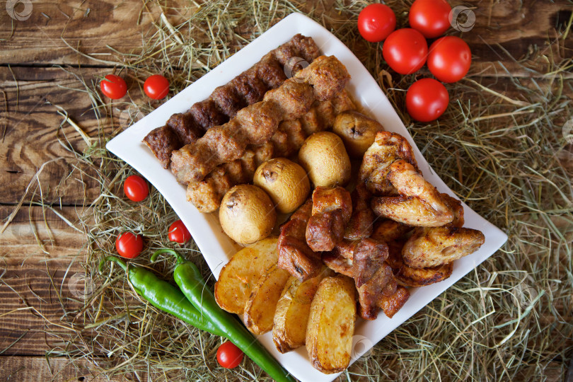 Скачать Мясные закуски, овощи и грибы, запеченные на гриле, лежат на большой тарелке. фотосток Ozero