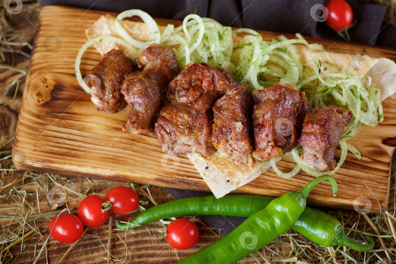 Скачать Приготовленные на гриле мясные шашлыки выложите на деревянную доску. Украсьте овощами и тонким хлебом. Приготовьте по рецептам шеф-повара. фотосток Ozero