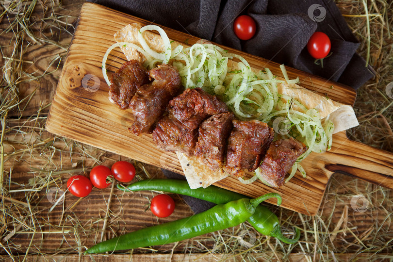 Скачать Приготовленные на гриле мясные шашлыки выложите на деревянную доску. Украсьте овощами и тонким хлебом. Приготовьте по рецептам шеф-повара. фотосток Ozero