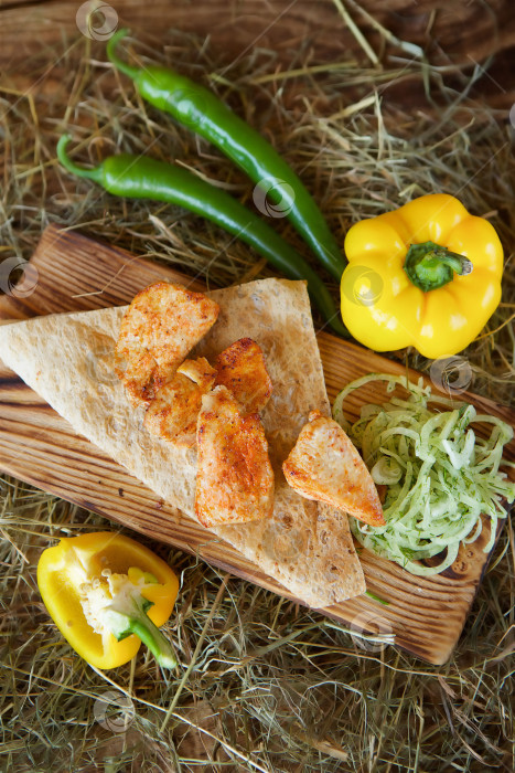Скачать Кусочки мяса, приготовленного на гриле, на лаваше, подаются со свежим перцем и салатом на деревянной доске фотосток Ozero