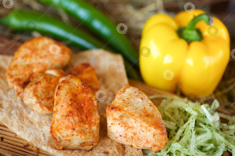 Скачать Кусочки мяса, приготовленного на гриле, на лаваше, подаются со свежим перцем и салатом на деревянной доске фотосток Ozero