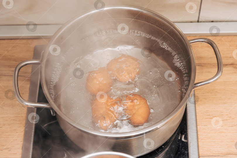 Скачать Коричневые куриные яйца варятся в металлических горшочках на кухонной плите, готовя полезный завтрак фотосток Ozero