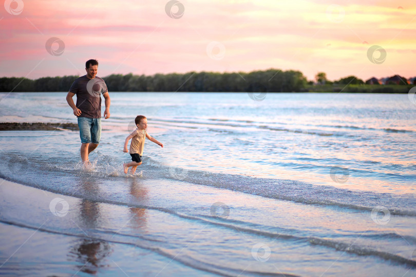 Скачать счастливый папа бежит за своим маленьким сыном 4-5 лет по берегу реки на закате фотосток Ozero