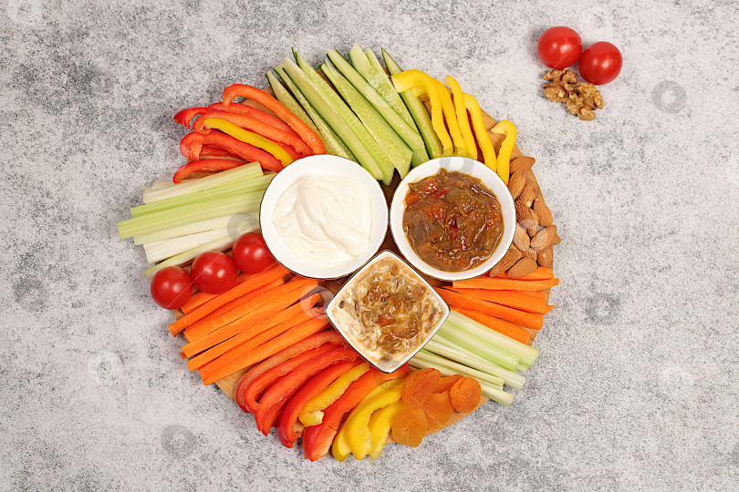 Скачать Кухня здорового питания на фоне миски с хумусом и палочками из сырых овощей, орехами и курагой. Блюдо с хумусом и закусками, ближневосточное блюдо, традиционные веганские закуски., фотосток Ozero
