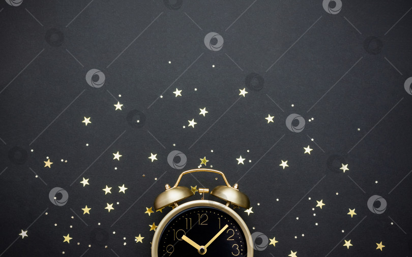 Скачать Золотой винтажный будильник, украшенный звездным конфетти на темном фоне. Концепция сказок на ночь. Выборочный фокус, пространство для копирования. фотосток Ozero