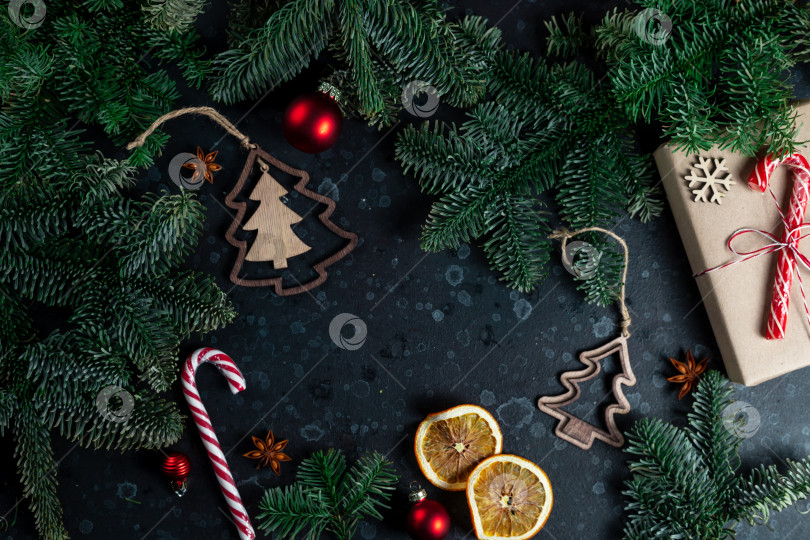 Скачать На столе лежит подарок, окруженный ветками рождественской елки, деревянными игрушками и специями фотосток Ozero