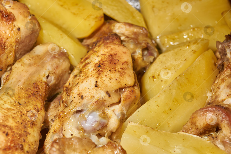 Скачать Запеченные в духовке кусочки курицы с ломтиками картофеля и смесью приправ. фотосток Ozero