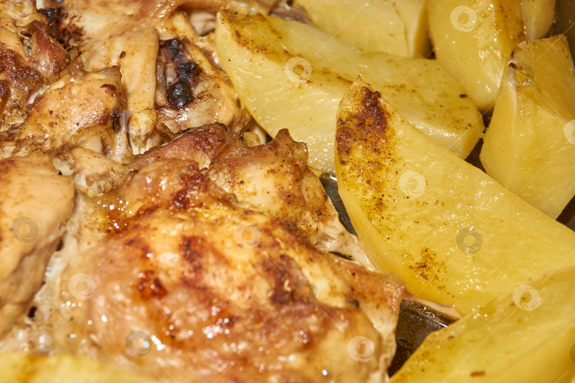 Скачать Запеченные в духовке кусочки курицы с ломтиками картофеля и смесью приправ. фотосток Ozero