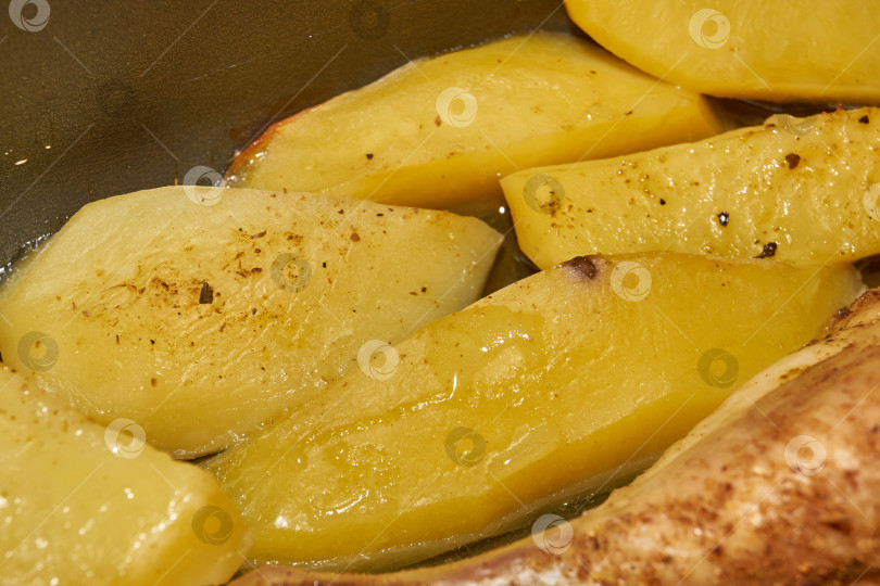 Скачать Запеченные в духовке кусочки курицы с ломтиками картофеля и смесью приправ. фотосток Ozero