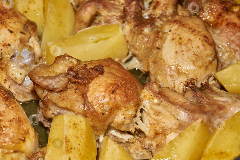 Скачать Запеченные в духовке кусочки курицы с ломтиками картофеля и смесью приправ. фотосток Ozero