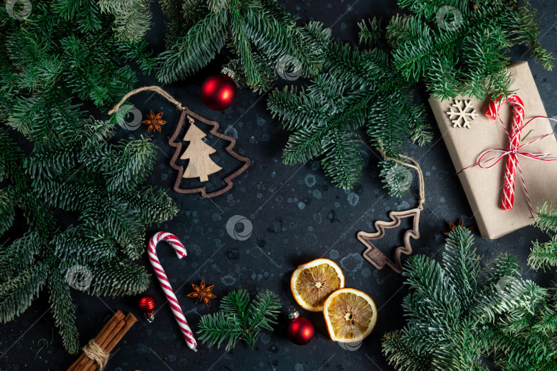 Скачать На столе лежит подарок, окруженный ветками рождественской елки, деревянными игрушками и специями фотосток Ozero