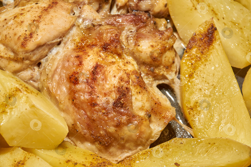 Скачать Запеченные в духовке кусочки курицы с ломтиками картофеля и смесью приправ. фотосток Ozero