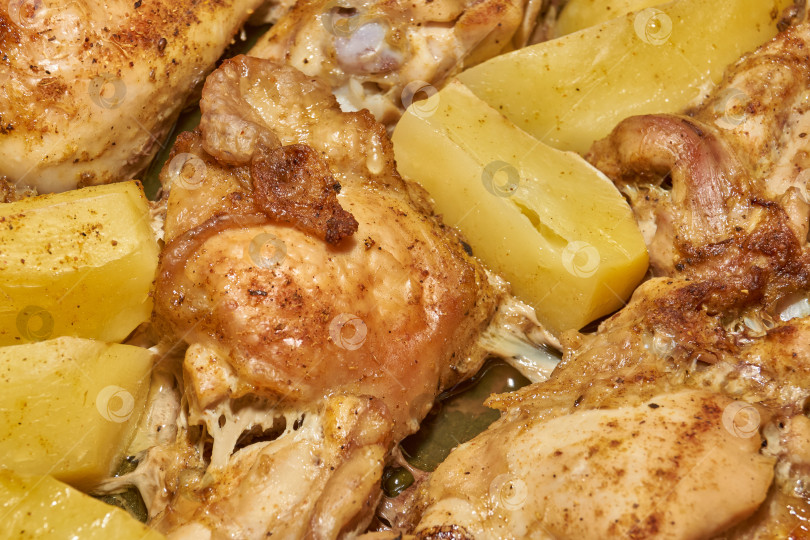 Скачать Запеченные в духовке кусочки курицы с ломтиками картофеля и смесью приправ. фотосток Ozero
