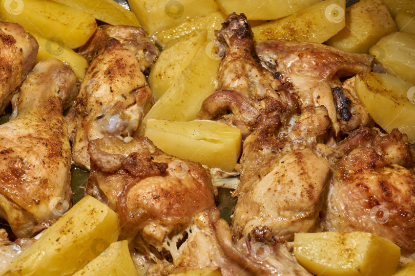 Скачать Запеченные в духовке кусочки курицы с ломтиками картофеля и смесью приправ. фотосток Ozero