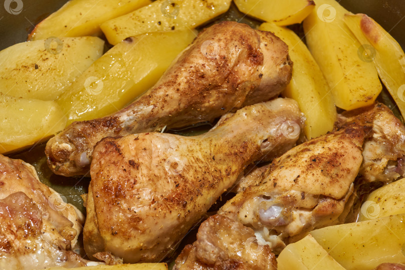 Скачать Запеченные в духовке кусочки курицы с ломтиками картофеля и смесью приправ. фотосток Ozero