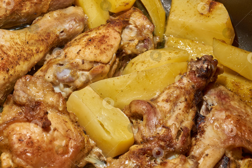 Скачать Запеченные в духовке кусочки курицы с ломтиками картофеля и смесью приправ. фотосток Ozero