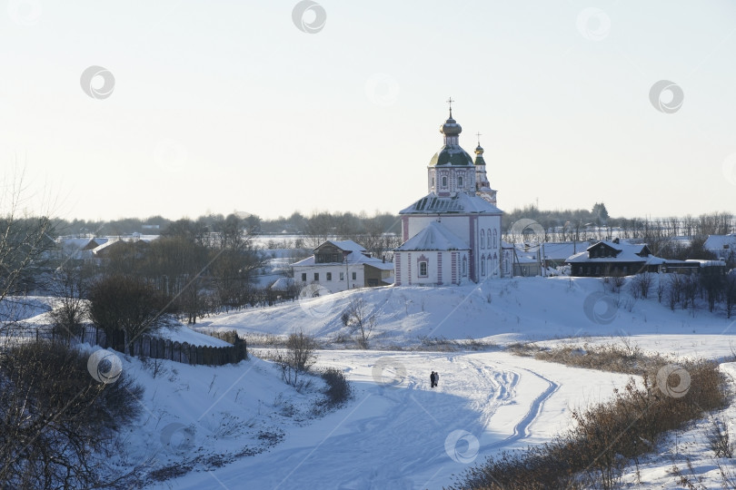 Скачать Деревенский зимний пейзаж с замерзшей рекой и православной церковью на холме. фотосток Ozero