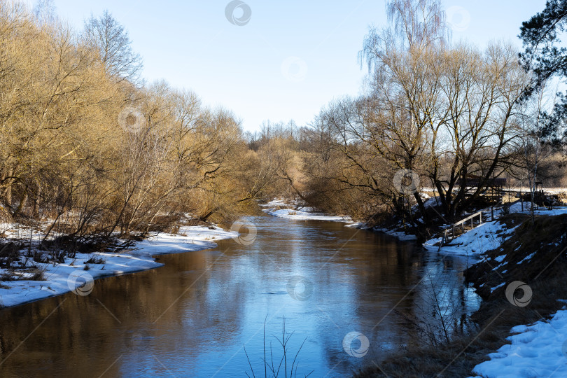 Скачать Безмятежная и отражающая воду река, спокойная ранней весной, с умиротворяющими природными пейзажами фотосток Ozero