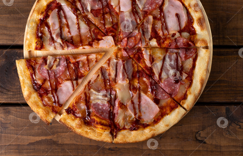 Скачать Пицца на тарелке на деревянном фоне, нарезанная кусочками фотосток Ozero
