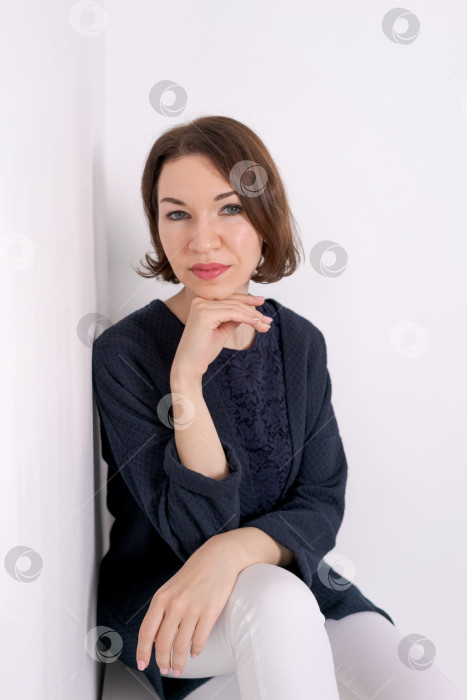 Скачать Женский портрет с мягкой улыбкой и прижатой к подбородку рукой в светлой студии в стиле минимализма фотосток Ozero