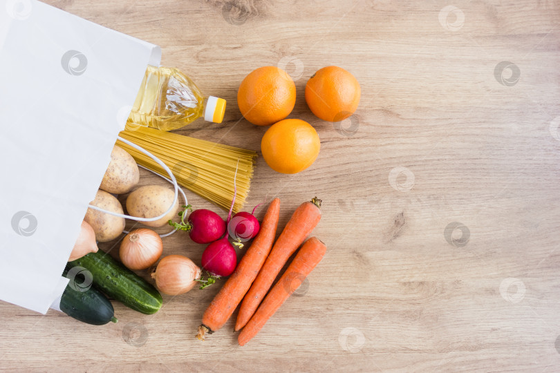 Скачать Продукты в белом картонном пакете на деревянном столе. Концепция пожертвований продуктов питания и волонтерства. фотосток Ozero