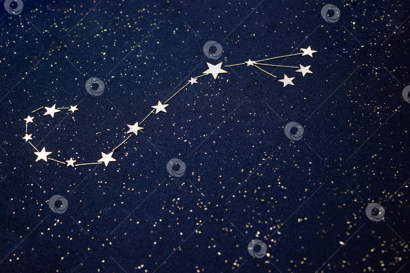 Скачать Знак зодиака Скорпион на темном небе крупным планом. Аппликация выполнена из конфетти в виде серебряных звездочек и зернистого синего картона. Концепция гороскопа. Избирательный фокус. фотосток Ozero