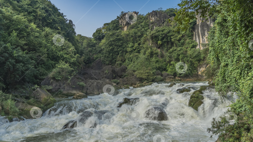 Скачать Бурная горная река. Бурные потоки белой воды бурлят и пенятся на валунах фотосток Ozero