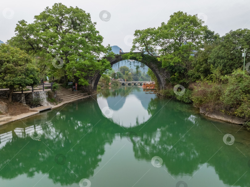 Скачать Каменный арочный мост Фули перекинут через спокойную зеленую реку. Гуйлинь, Китай. фотосток Ozero