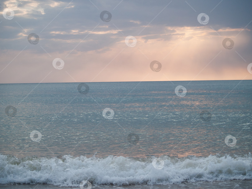 Скачать Спокойное море с легкой рябью и пенистыми волнами у берега. Облачное небо на горизонте, сквозь которое проникает мягкий свет. Идеально подходит для отдыха и прогулок на природе. фотосток Ozero