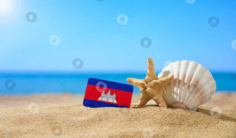 Скачать Тропический пляж с ракушками и флагом Камбоджи. Концепция райского отдыха на пляжах Камбоджи. фотосток Ozero