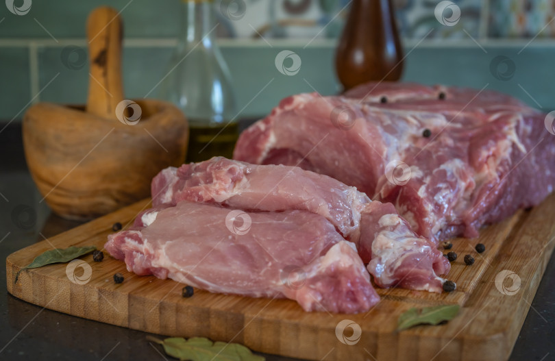 Скачать Свежая свиная мякоть с надрезанными порциями для обжаривания лежит на разделочной доске фотосток Ozero
