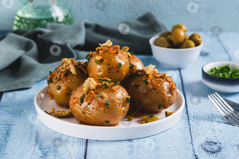 Скачать Запеченный молодой картофель с зеленью и маслинами на тарелке на столе фотосток Ozero