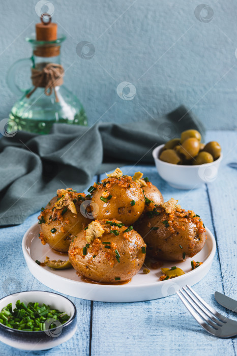 Скачать Запеченный молодой картофель с зеленью и оливками на тарелке на столе, вид сверху фотосток Ozero