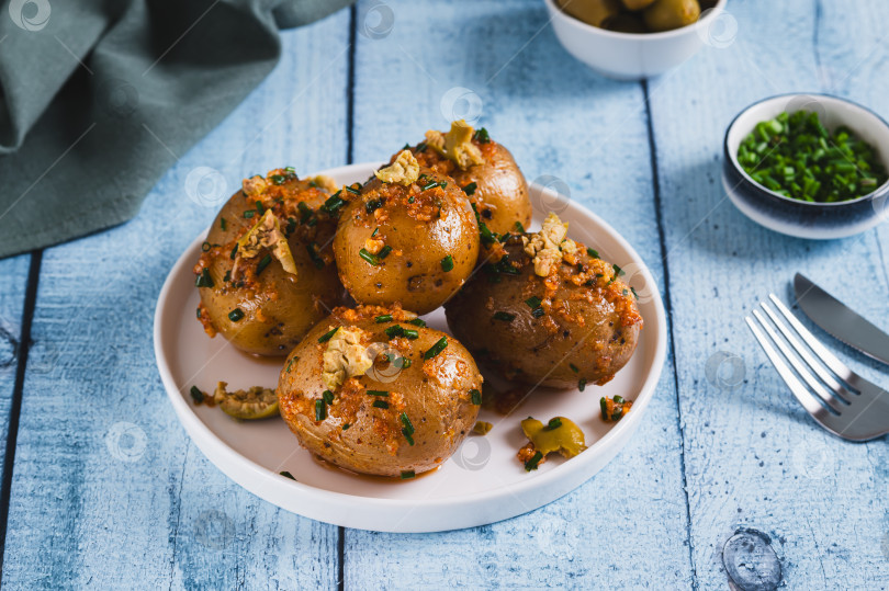 Скачать Запеченный молодой картофель с зеленым луком и оливками на тарелке на столе фотосток Ozero
